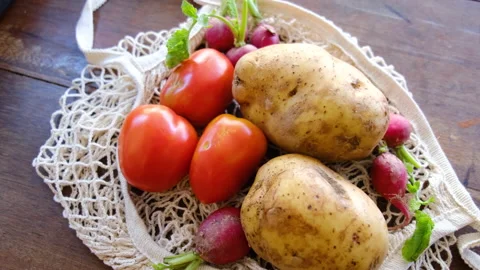 Vegetables in eco-friendly string reusable net mesh bag on wooden background Video stock 138831426