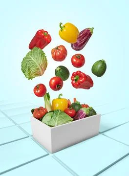 Vegetables falling into a box on blue background Stock Photos