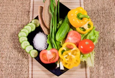 Vegetables with greenery, rye bread and large salt on a dish Stock Photos
