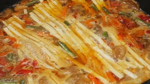 Vegetables with minced meat are stewed in a frying pan with udon in spices .. Stock Footage 303591979