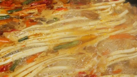 Vegetables with minced meat are stewed in a frying pan with udon in spices .. Vidéo 304518500