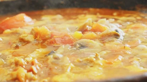 Vegetables simmer with chicken in a deep cast-iron skillet, simmering in a .. Video stock 329435978