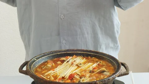 Vegetables simmer in a deep cast-iron skillet with chicken and udon, stirri.. Stock Footage 332432667