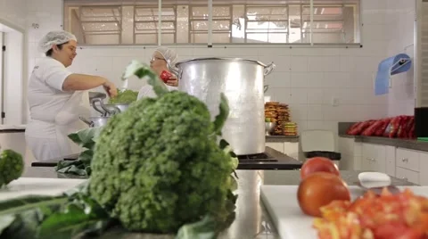 Vegetables on the table and cooks cooking in the background Stock Footage 47573096