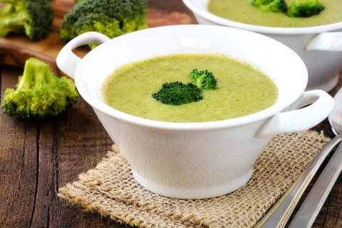 Vegetarian broccoli cream soup in a white bowl on rustic wooden kitchen table Stock Photos