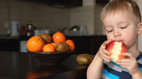 Vegetarian child eats apple and choose tangerine from fresh fruits, kid kitchen Video stock 126998313