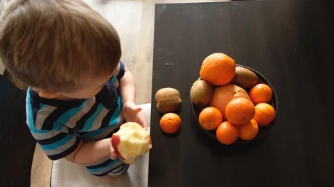 Vegetarian child eats apple for breakfast in morning, top view above Video stock 126998305