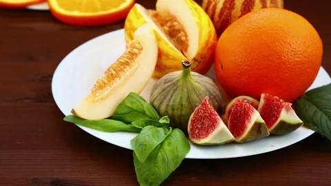 Vegetarian diet. On the table lie fruit: Vietnamese melon, figs, kiwi, orange Stock Footage 79668136