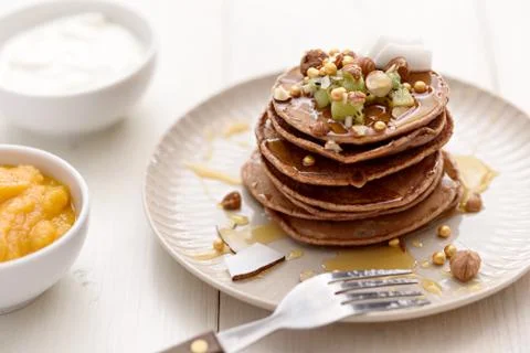 Vegetarian stack of chocolate chip pancakes with kiwi, nuts and honey with so Stock Photos