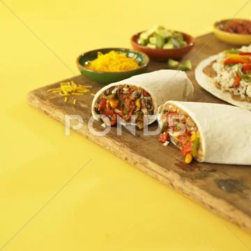 Veggie Burrito Halved with Bowls of Filling Stock Photos