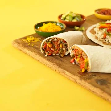 Veggie Burrito Halved with Bowls of Filling Stock Photos