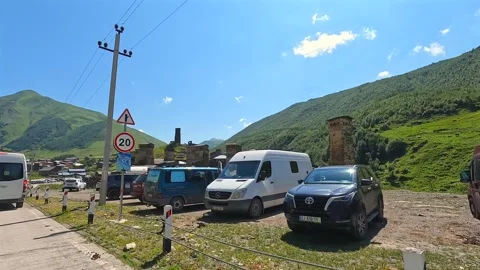 Vehicle driving in side view past Svan towers in Ushguli Stock Footage 343776120