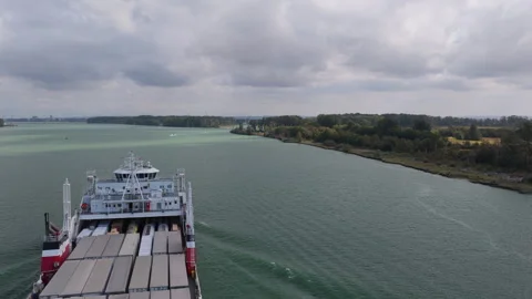 Vehicle ferry carrying cargo trailers on wide inlet, Medium Aerial Tracking View Stock Footage 346252168