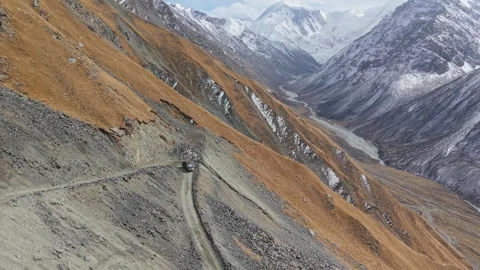 Vehicle navigating rugged mountain terrain with dynamic aerial camera movement Stock Footage 320395745