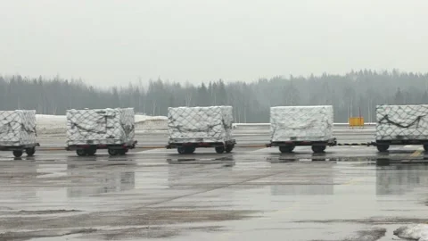 A vehicle pulls cargo carts at the snowy Helsinki Airport, Finland Stock Footage 210321734