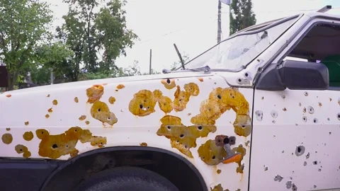 A vehicle severely damaged with rust and bullet holes, showing signs Stock Footage 276593341