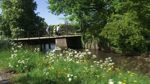 Vehicle shot - Cyclists on a small bridge across canal Stock Footage 59190228
