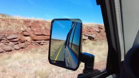 Vehicle side mirror reflecting desert road drive in Naukluft National Park Vidéo 323919163