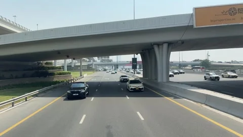 Vehicle traffic flows through Dubai's streets with cars changing lanes contin 스톡 동영상 313388423