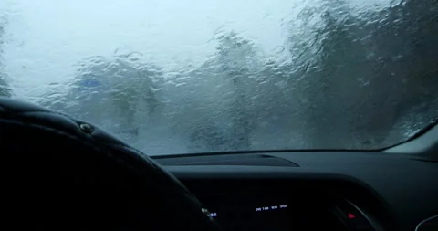 Vehicle windshield wipers clearing heavy rain during a storm on a city road Video stock 342278914