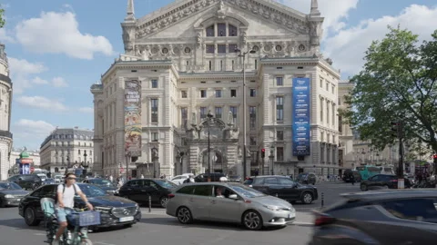 Vehicles and scooters drive through a busy intersection by Palais Opera Garnier Stock Footage 336721765