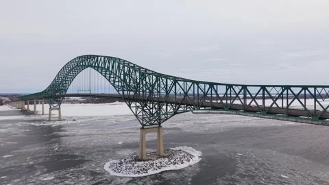 Vehicles crossing long bridge over frozen winter river aerial Stock Footage 329395603