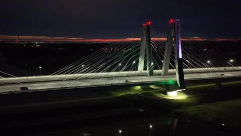 Vehicles crossing over cable-stayed bridge at night illuminated by streetlights Видео 346948136