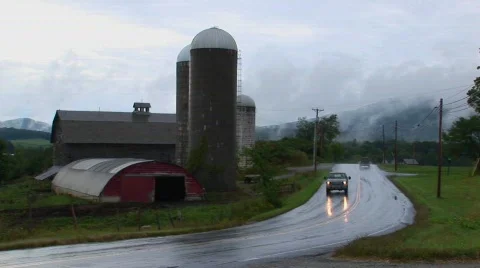 Vehicles drive pass a barn on a cloudy and rainy day. Stock-Footage 441522
