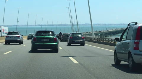 Vehicles drive steadily on Vasco da Gama bridge with a view of the shoreline Stock Footage 284341768
