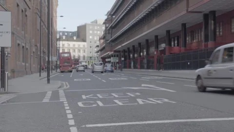 Vehicles driving down a busy city street past Keep Clear road marking 動画素材 342564544