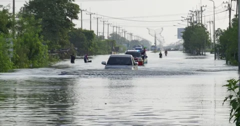 Vehicles driving through deep floodwaters submerging rural asphalt road during 스톡 동영상 348776592