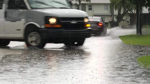 Vehicles Driving through Flood Puddle During Rain Sprinkles Stock Footage 219225188
