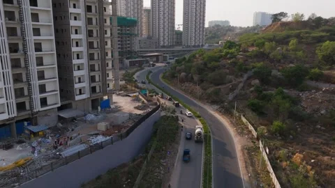Vehicles moving on S shape curved road with under construction tower building Stock Footage 339644639