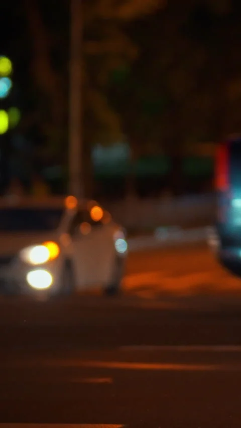 Vehicles navigate a busy city intersection during nighttime hours while glow Video stock 347073802