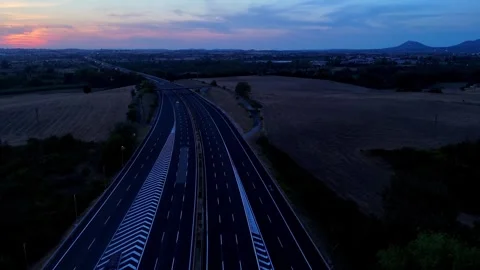 Vehicles navigating a twilight highway surrounded by scenic fields Stock Footage 282881086