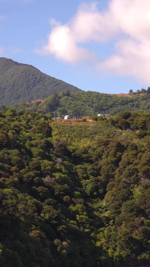 Vehicles parked on a forested hillside under a blue sky. Stock Footage 312513616