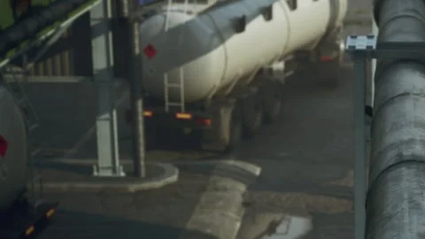 Vehicles parked in a loading area near storage tanks in an industrial facility Stock Footage 344110122