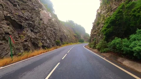 A vehicle's perspective navigating a lush green mountain road, winding through s Stock Footage 335242339