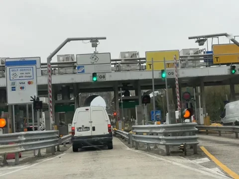 Vehicles queue at a busy highway toll station, with signs indicating self-s.. Video stock 328389879