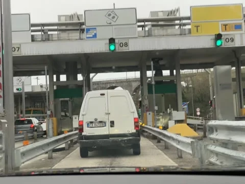 Vehicles queue at a modern toll plaza with overhead signage and traffic lig.. Stock Footage 328389754