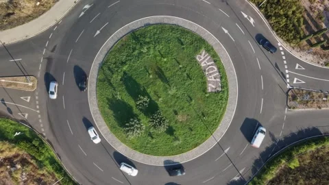 Vehicles travel through circular intersection in Zadar, Croatia, passing grassy Stock Footage 347859100