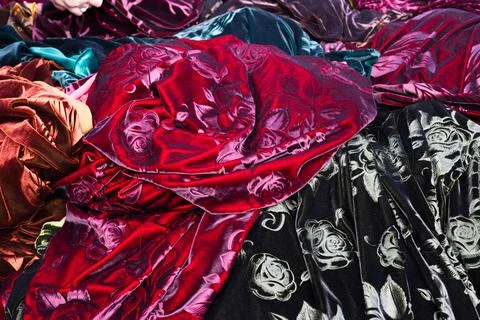 Velvet fabrics with embossed rose patterns piled at a bazaar in Bukhara, Uz.. Stock Photos