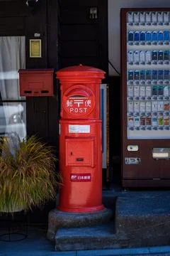 A vending machine next to a postbox on the side of a sidewalk Foto stock