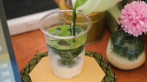 Vendor adding matcha solution to iced milk Видео 338273707