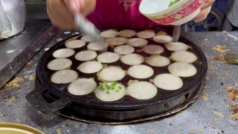 The vendor is adding spring onion topping on Thai coconut pancake. Stock Footage 270464061