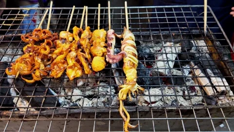 Vendor Adjusting Charcoal While Grilling Seafood Skewers at Thai Market 스톡 동영상 336389777