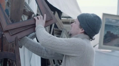 Vendor hanging old frames at antique fair Stock Footage 61410827