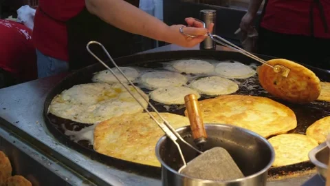 Vendor removing cooked Cong You Bing pancakes from large griddle in Shanghai Stock Footage 336442199