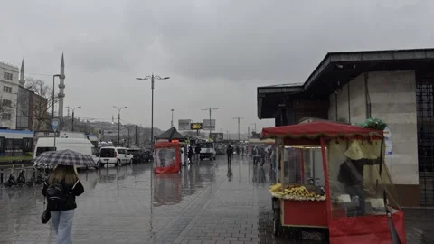 Vendor Sells Roasted Corn from Red Street Cart on Rainy Eminonu Square in Stock Footage 346324992