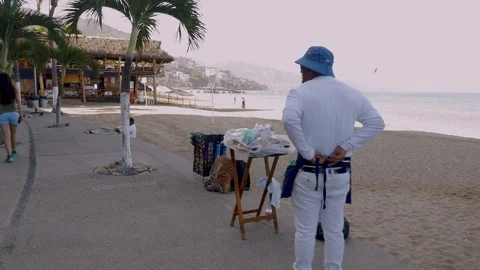 Vendor tying his apron getting ready for his day of selling on the beach Stock Footage 86884905